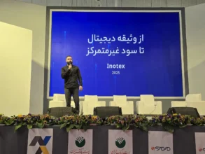 شاهین کاوه در حال سخنرانی روی صحنه در رویداد اینوتکس ۲۰۲۵، با صفحه‌نمایشی آبی که عبارت «از وثیقه دیجیتال تا سود غیرمتمرکز» را نمایش می‌دهد.