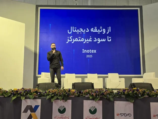 شاهین کاوه در حال سخنرانی روی صحنه در رویداد اینوتکس ۲۰۲۵، با صفحه‌نمایشی آبی که عبارت «از وثیقه دیجیتال تا سود غیرمتمرکز» را نمایش می‌دهد.
